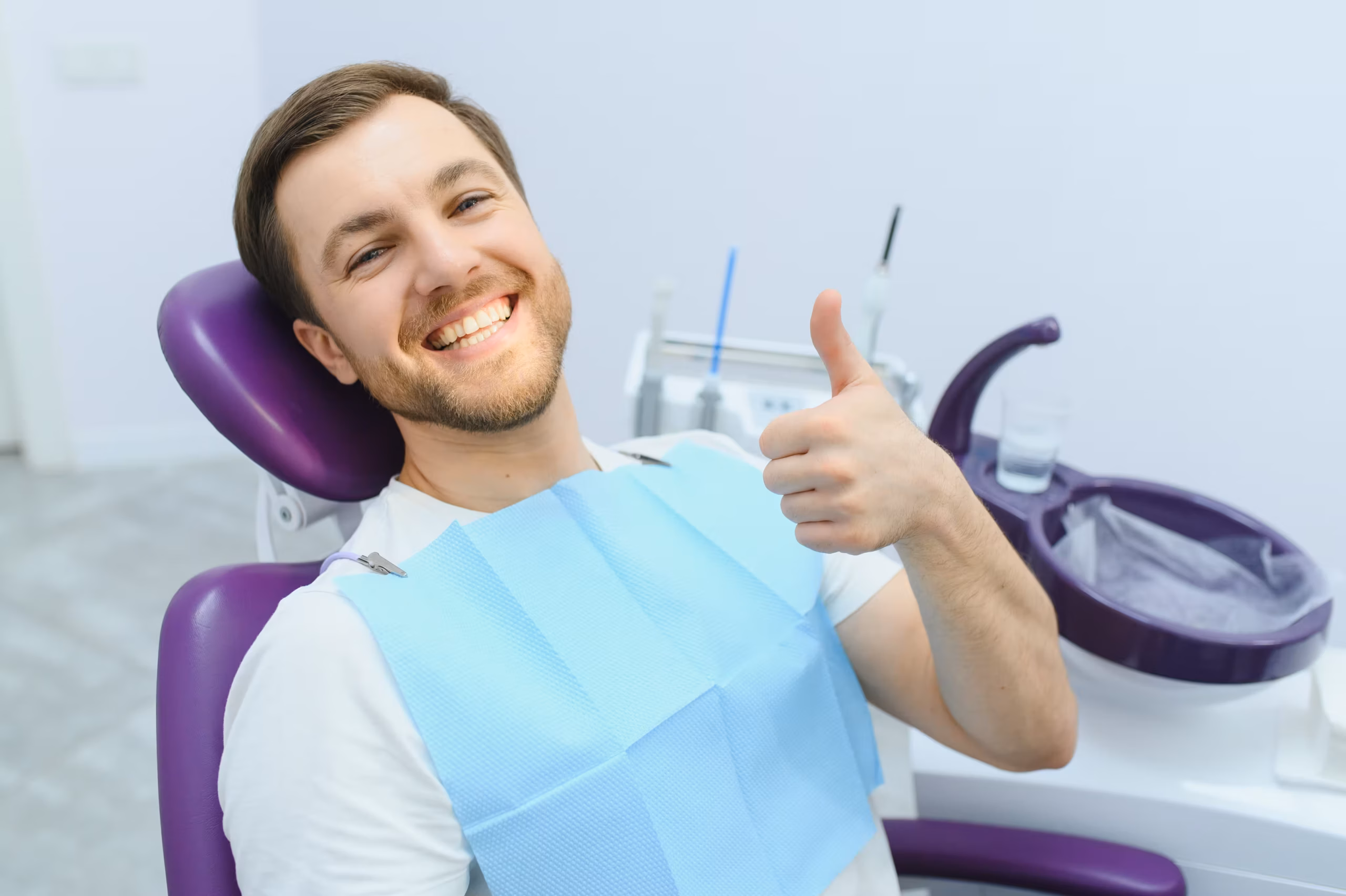 happy patient showing thumbs up after dental bonding treatment in clinic chair