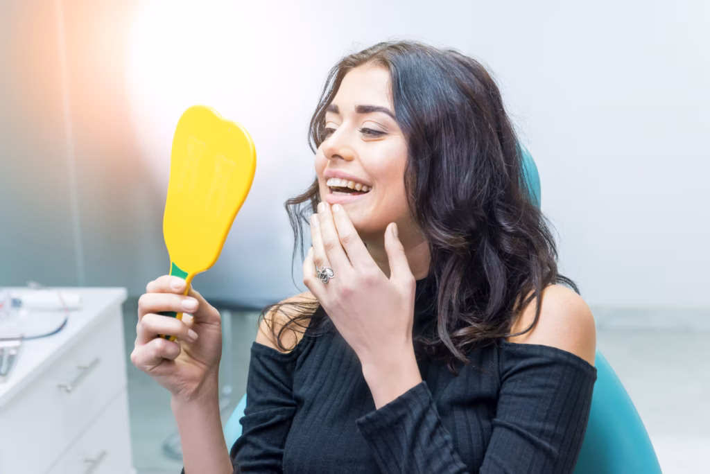 woman smiling in mirror checking teeth after inlay onlay dental restoration treatment