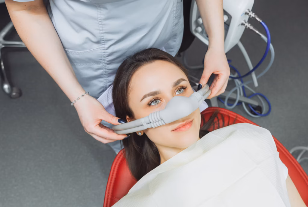 patient receiving nitrous oxide sedation with nasal mask being placed by dental professional before treatment