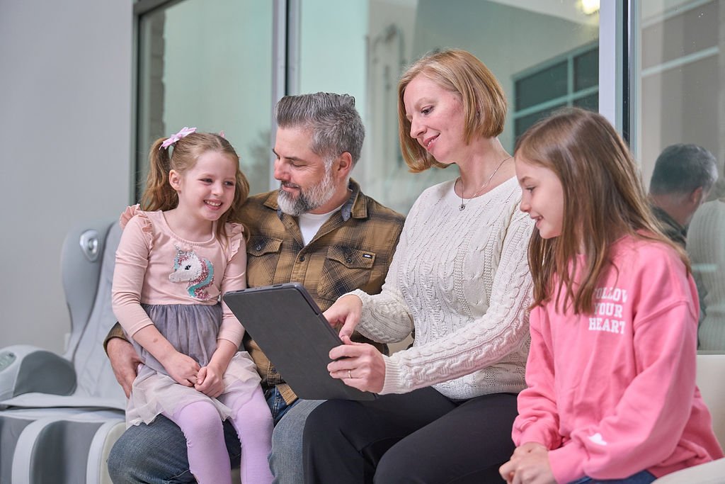 Smiling family sitting together in family dentist in San Antonio office, reviewing information on a tablet, showing a positive visit experience.