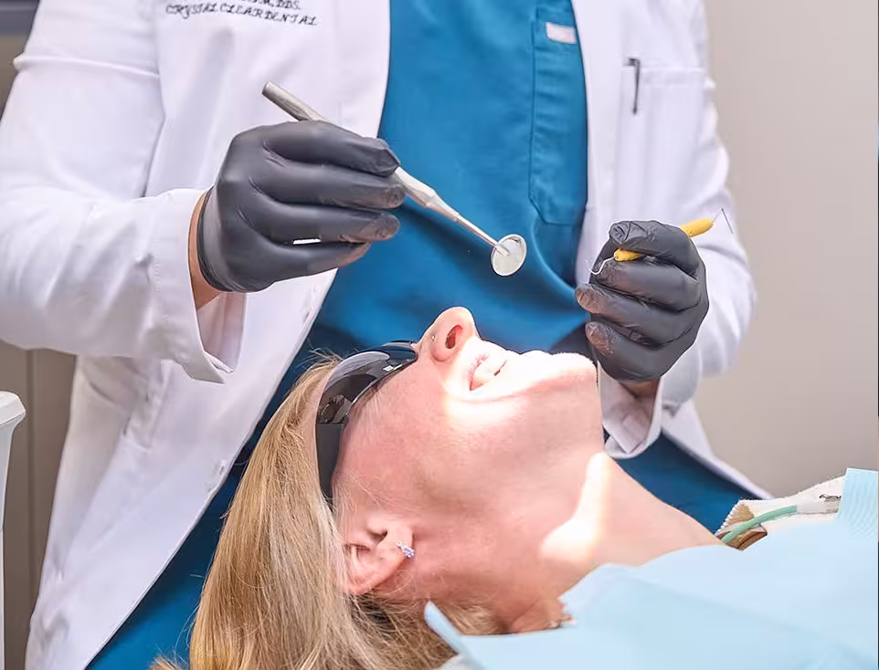 dentist examining patient teeth highlighting symptoms that may require root canal treatment