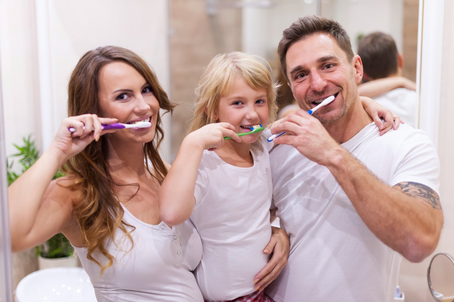 Happy family brushing their teeth together in a bathroom, promoting healthy habits with the help of a trusted family dentist San Antonio