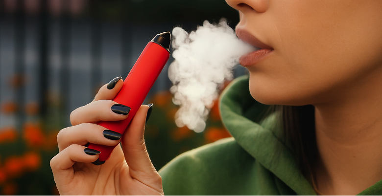Close-up of a red e-cigarette held in hand, used for vaping.
