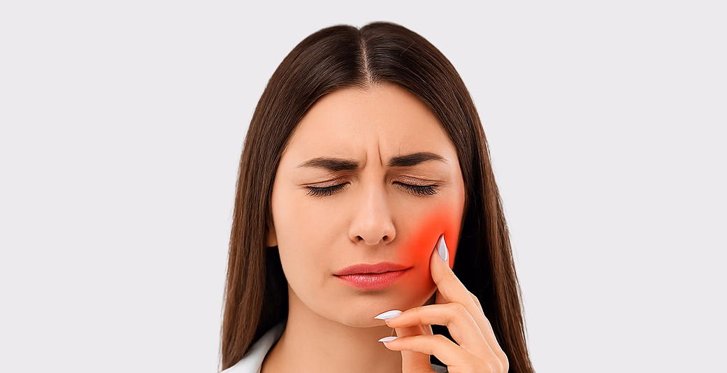 Woman with long brown hair touching her jaw in pain, highlighting dental discomfort or possible toothache.