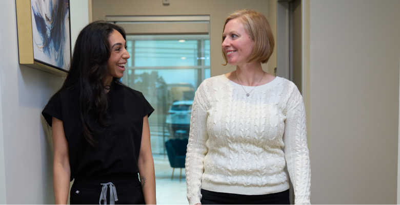 Two smiling individuals chatting in a clinic hallway, capturing a warm, candid moment that reflects positive patient experiences