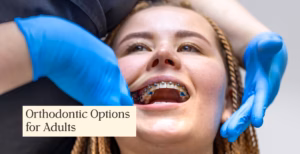 Adult patient receiving orthodontic treatment with metal braces, examined by a dental professional wearing blue gloves in a clinical setting.