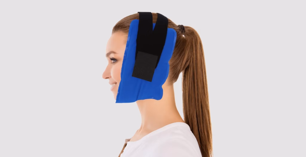 Person wearing therapeutic jaw wrap with straps, used for TMJ relief, dental recovery, or facial pain therapy.