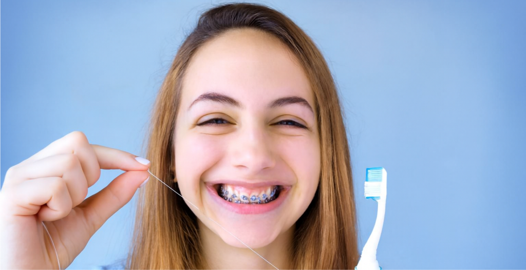 Person with braces holding a toothbrush and floss pick, showing tools for proper dental hygiene.