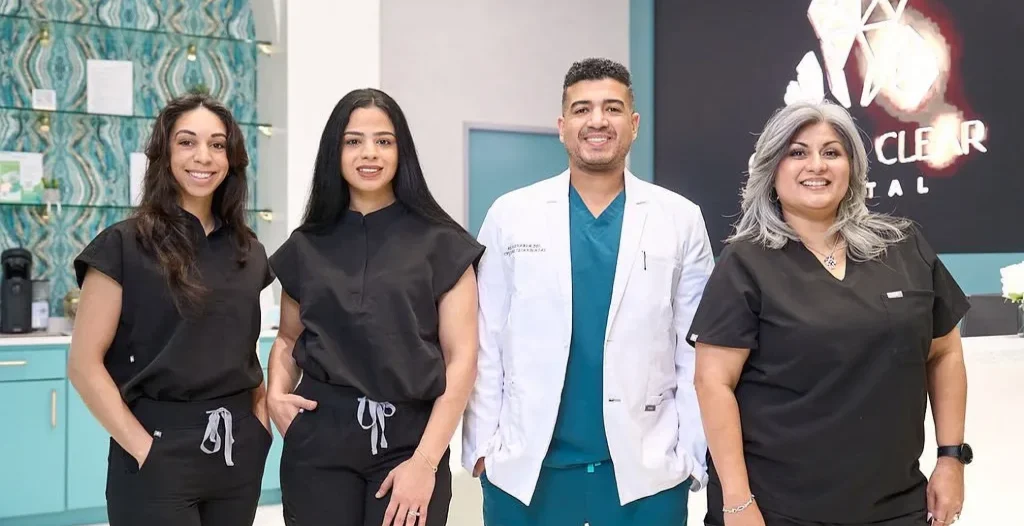 Dental team posing at Crystal Clear Dental clinic, with staff in scrubs and doctor in white coat.