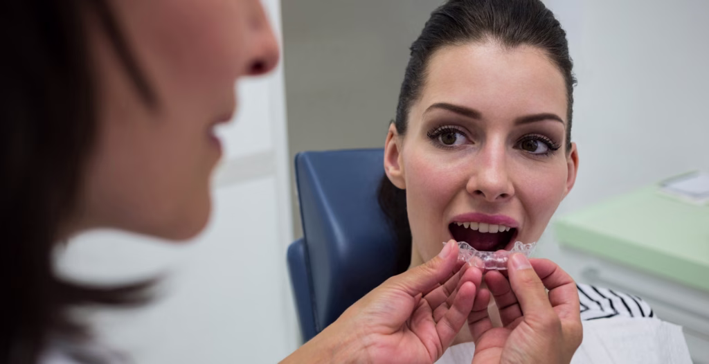 Clear aligner being demonstrated by dentist to patient during modern orthodontic consultation.