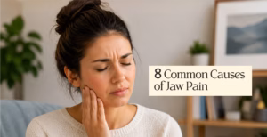 Person touching jaw due to pain, highlighting common causes of jaw discomfort and TMJ-related issues.