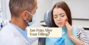 Dentist wearing mask looks at woman in dental chair holding her painful jaw. Text says 'Jaw Pain After Your Filling?'.
