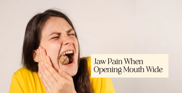 Woman holding her cheek in pain while biting a whole walnut, with text reading "Jaw Pain When Opening Mouth Wide".